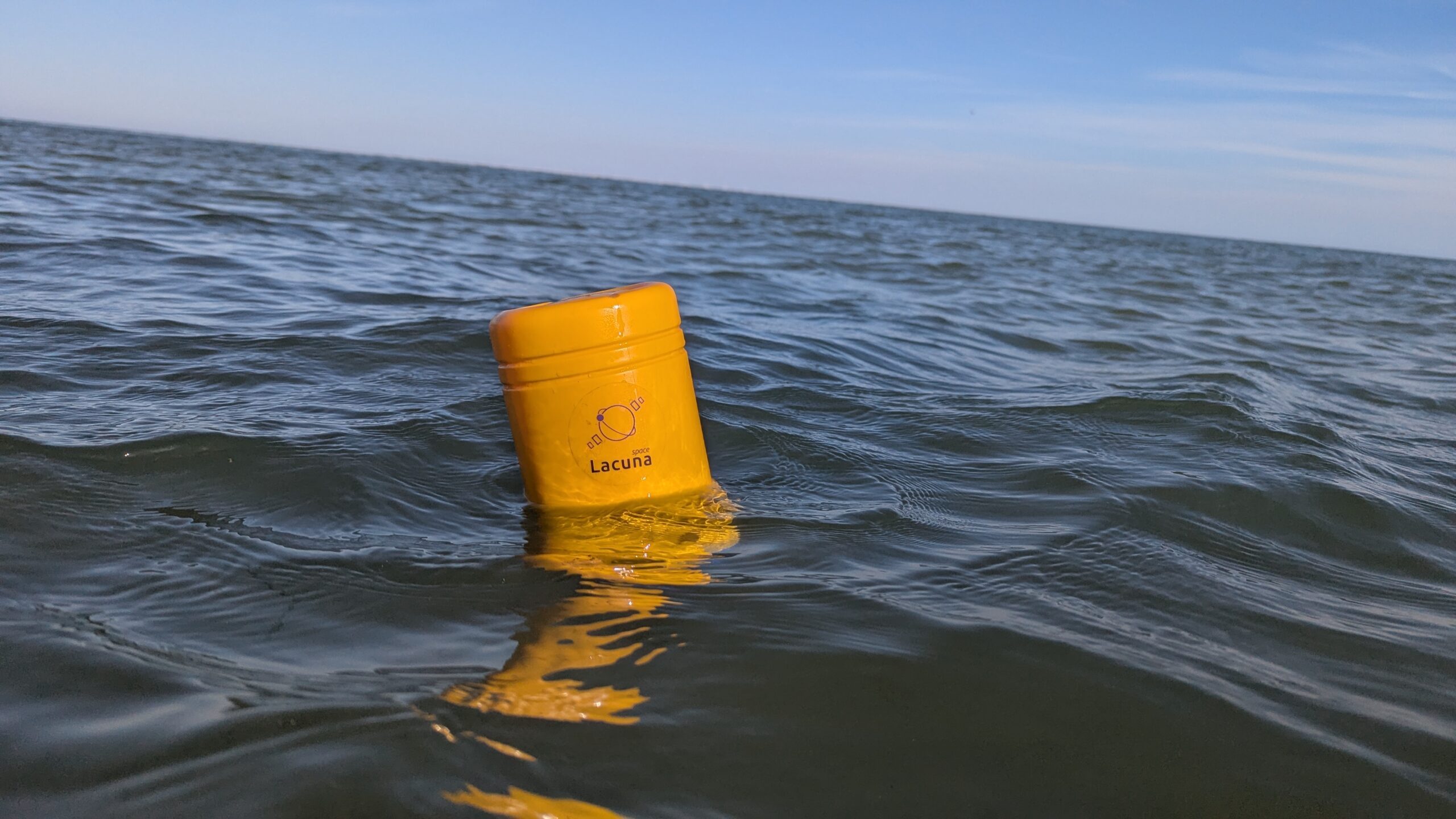 Yellow cylindrical Lacuna Space Satellite IoT sensor floating in the sea, providing low-power, direct-to-satellite LoRaWAN connectivity for maritime and Blue Economy monitoring.